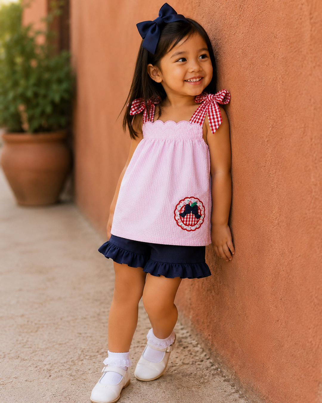 Young girl is leaning up against a reddish stucco wall.