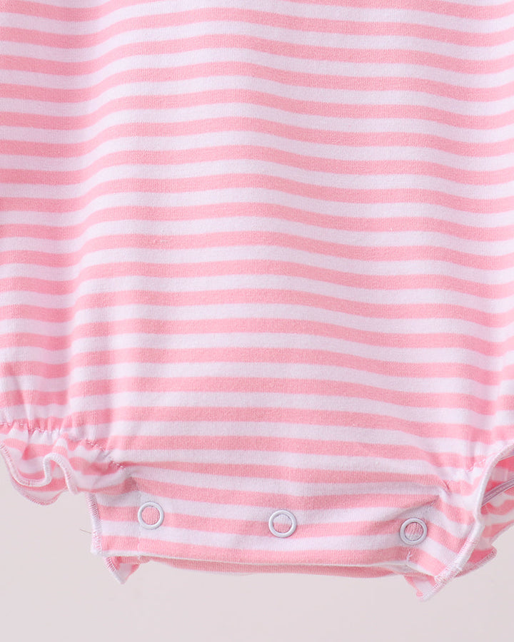 Close-up of a pink and white striped baby romper with ruffled leg openings and three snap closures at the crotch.