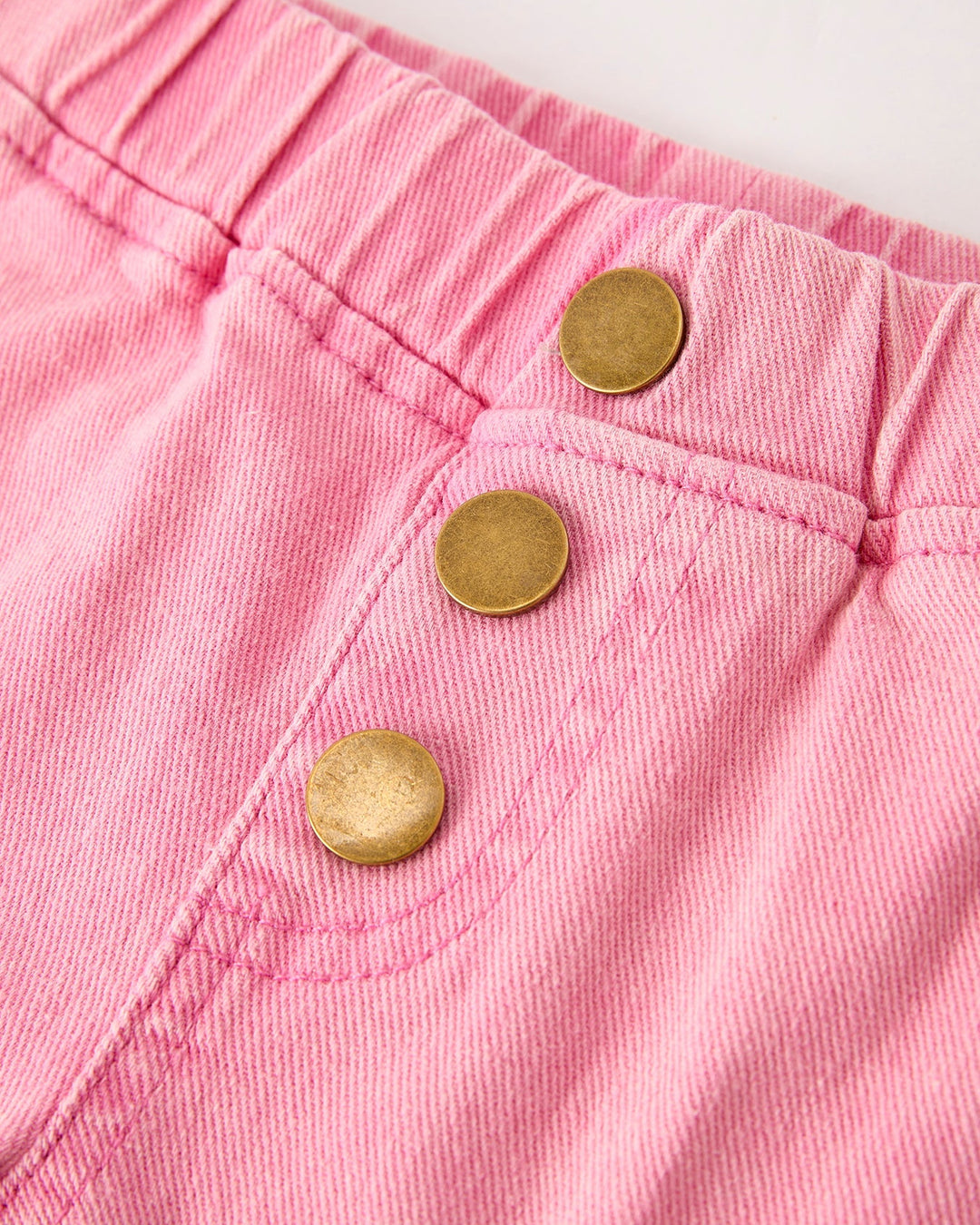Light pink waistband with three gold button closures and denim stitching