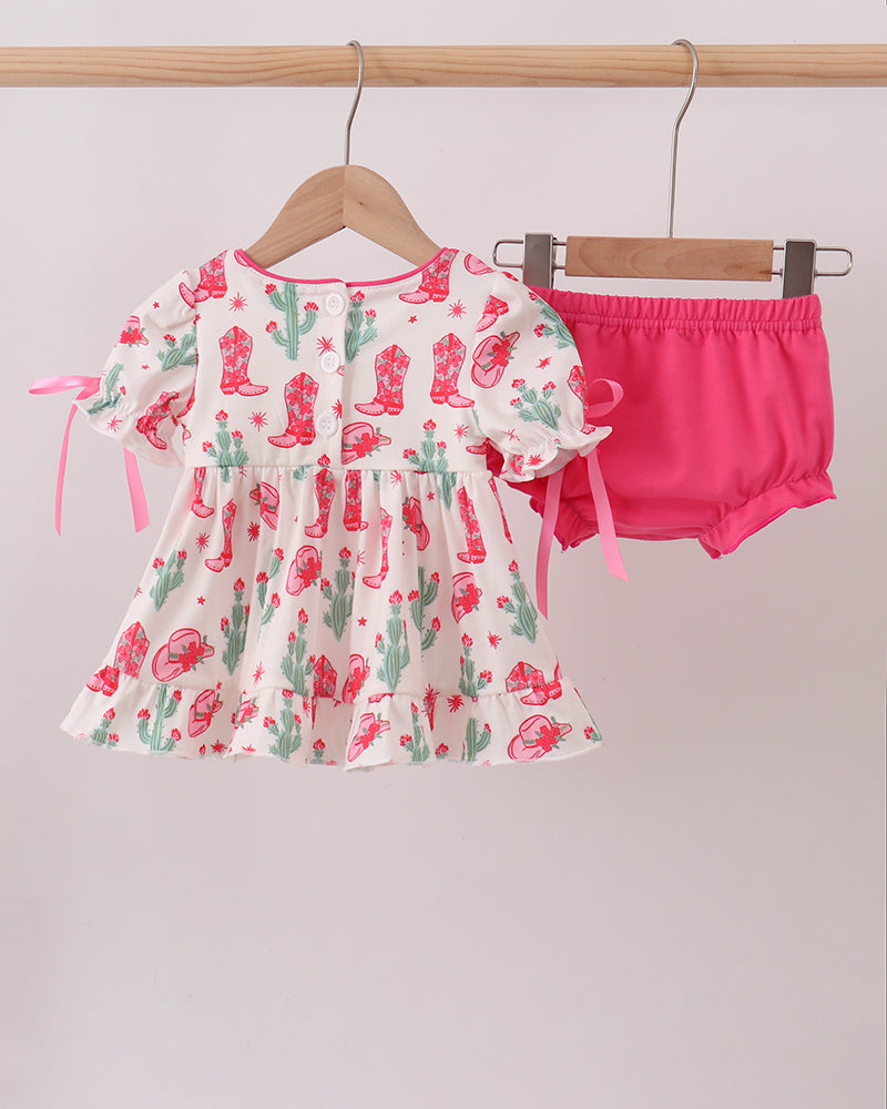 Baby outfit with floral top and pink bloomers on hangers against a white background