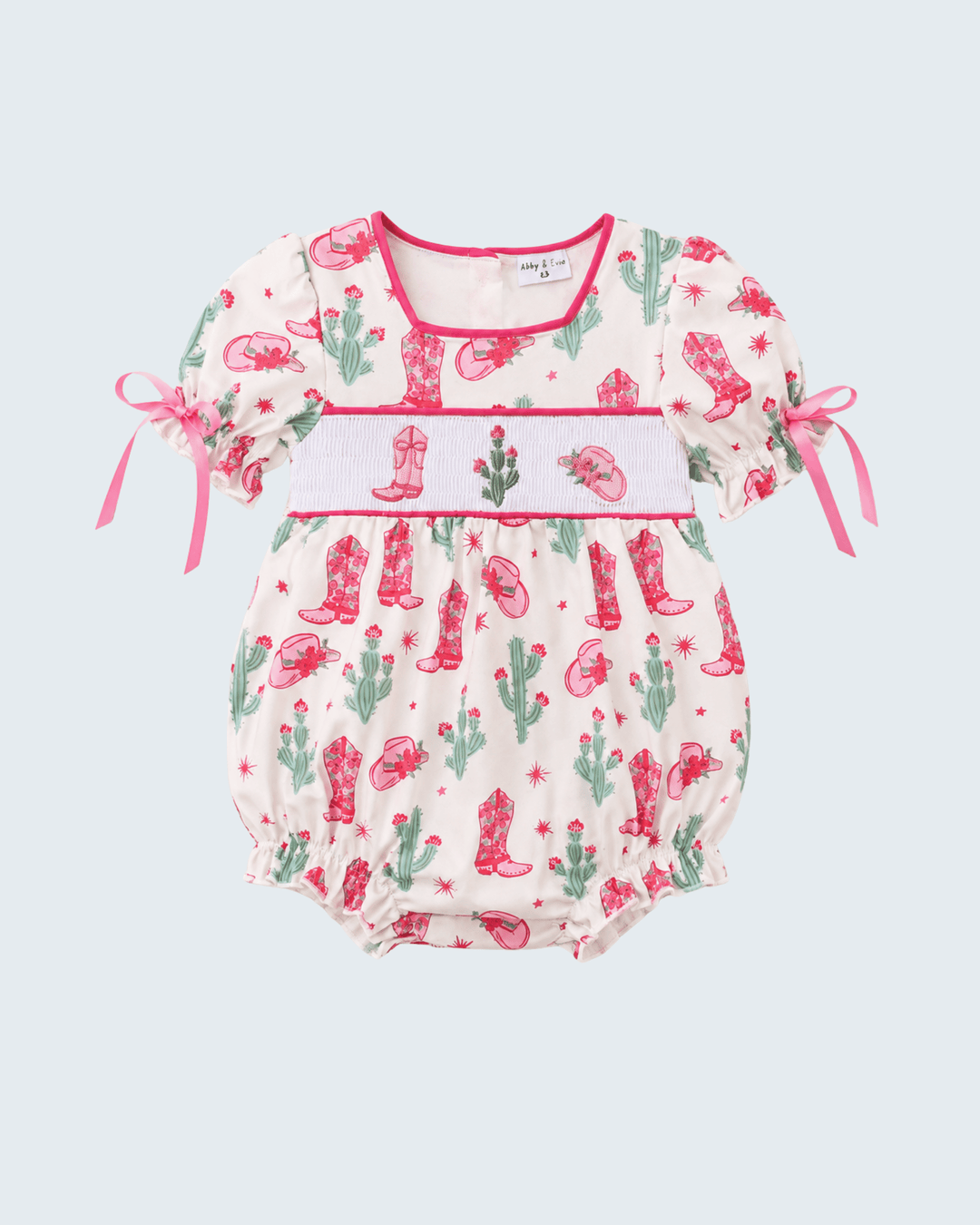 Baby romper with cactus and cowboy boot pattern on a light blue background