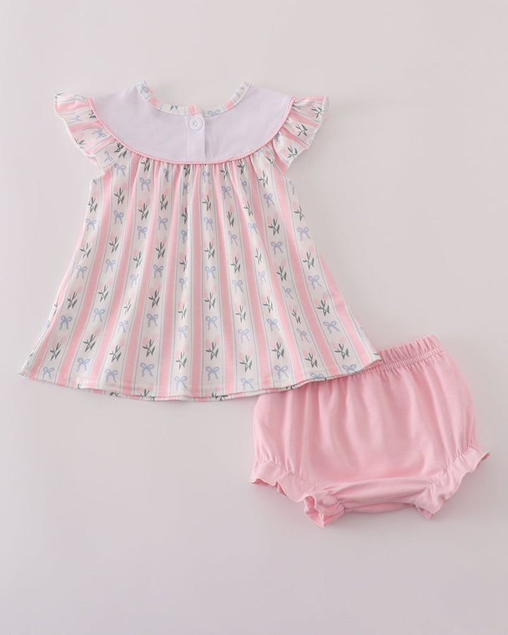 Baby dress with floral pattern and matching bloomers on a light gray background