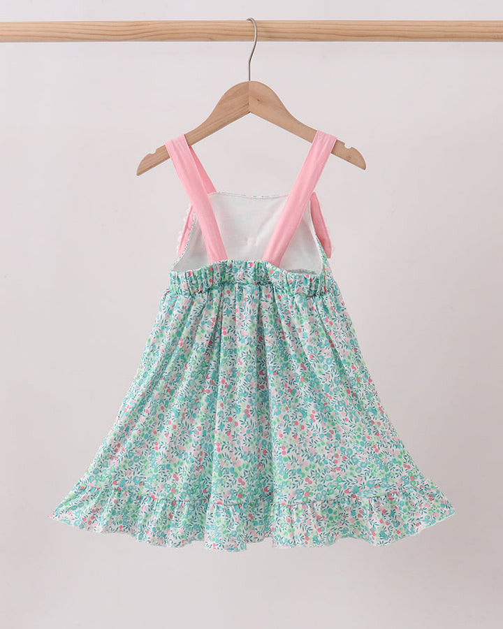 Floral dress with pink straps on a hanger against a plain background