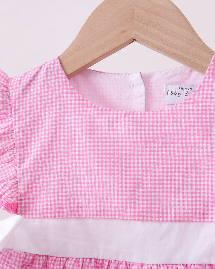 Pink checkered dress on a hanger with a visible brand label.