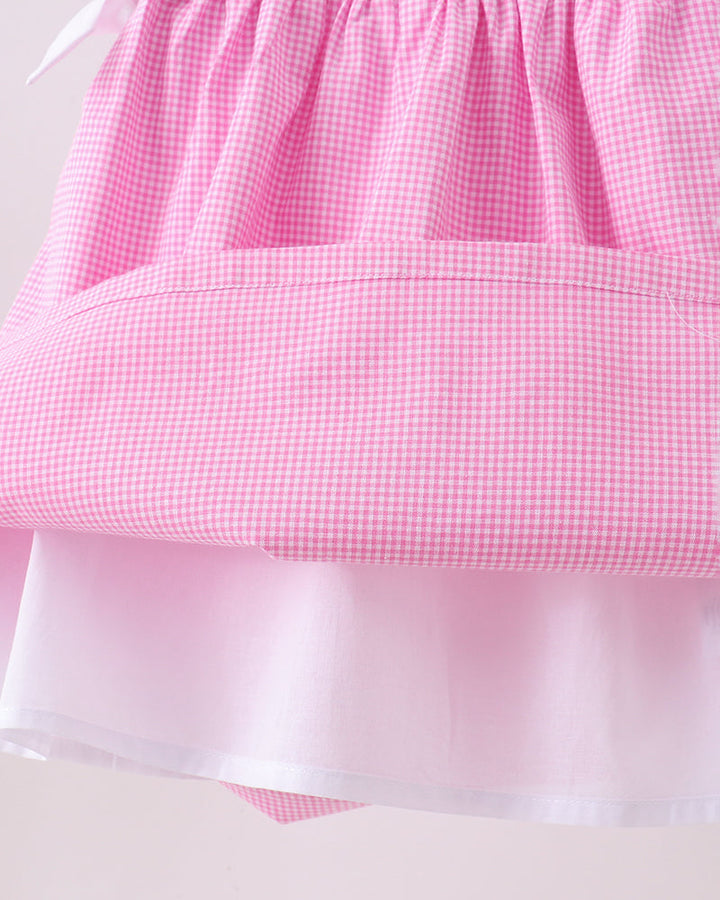 Close-up of a pink checkered fabric with a satin trim on a white background