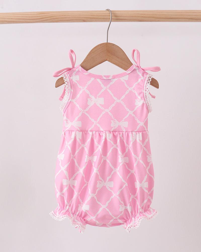 Pink romper with white patterns on a wooden hanger against a light background
