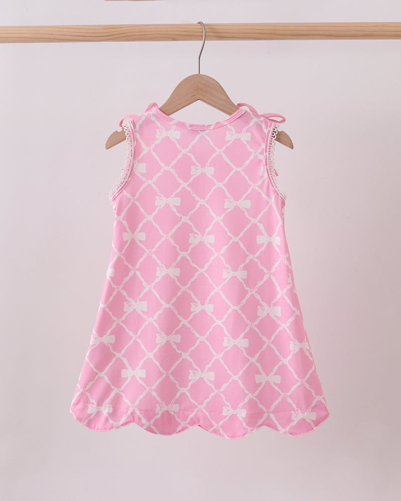 Pink dress with white patterns on a hanger against a plain background