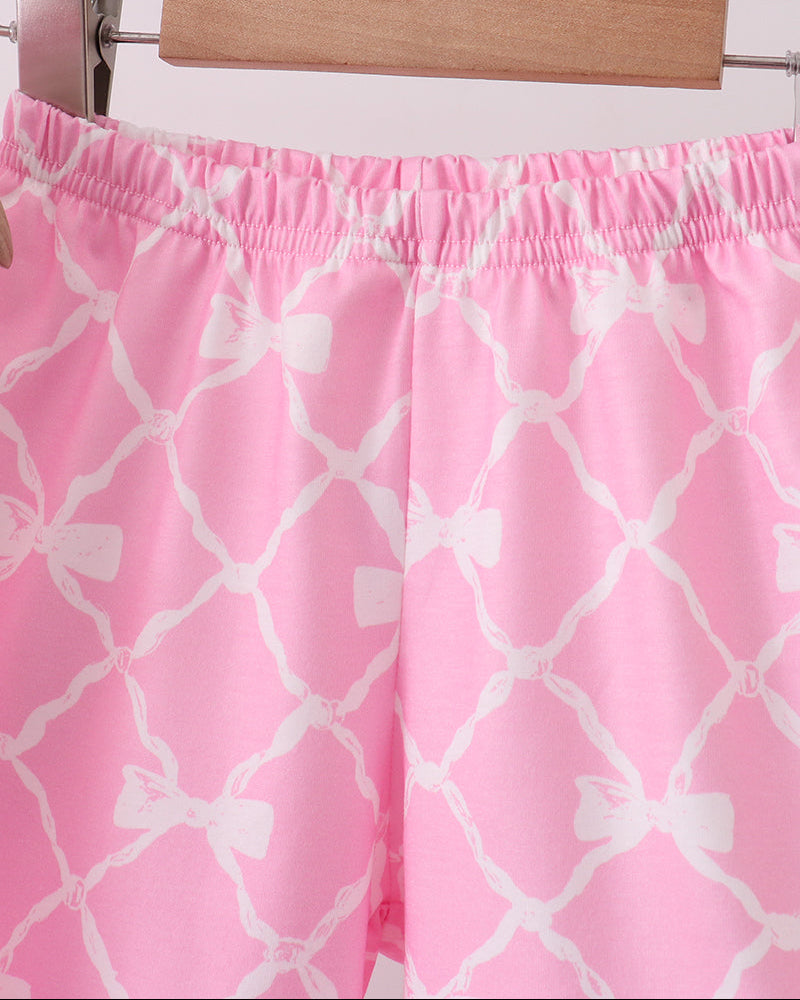 Pink shorts with white geometric pattern on a hanger against a white background