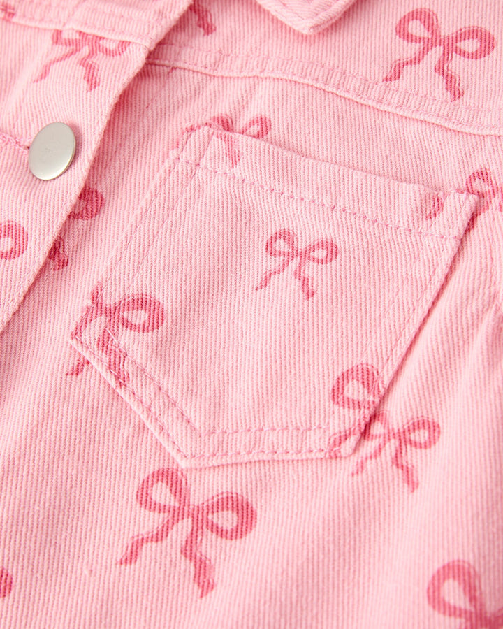 Pink denim jacket close-up: bow print fabric and stitched chest pocket