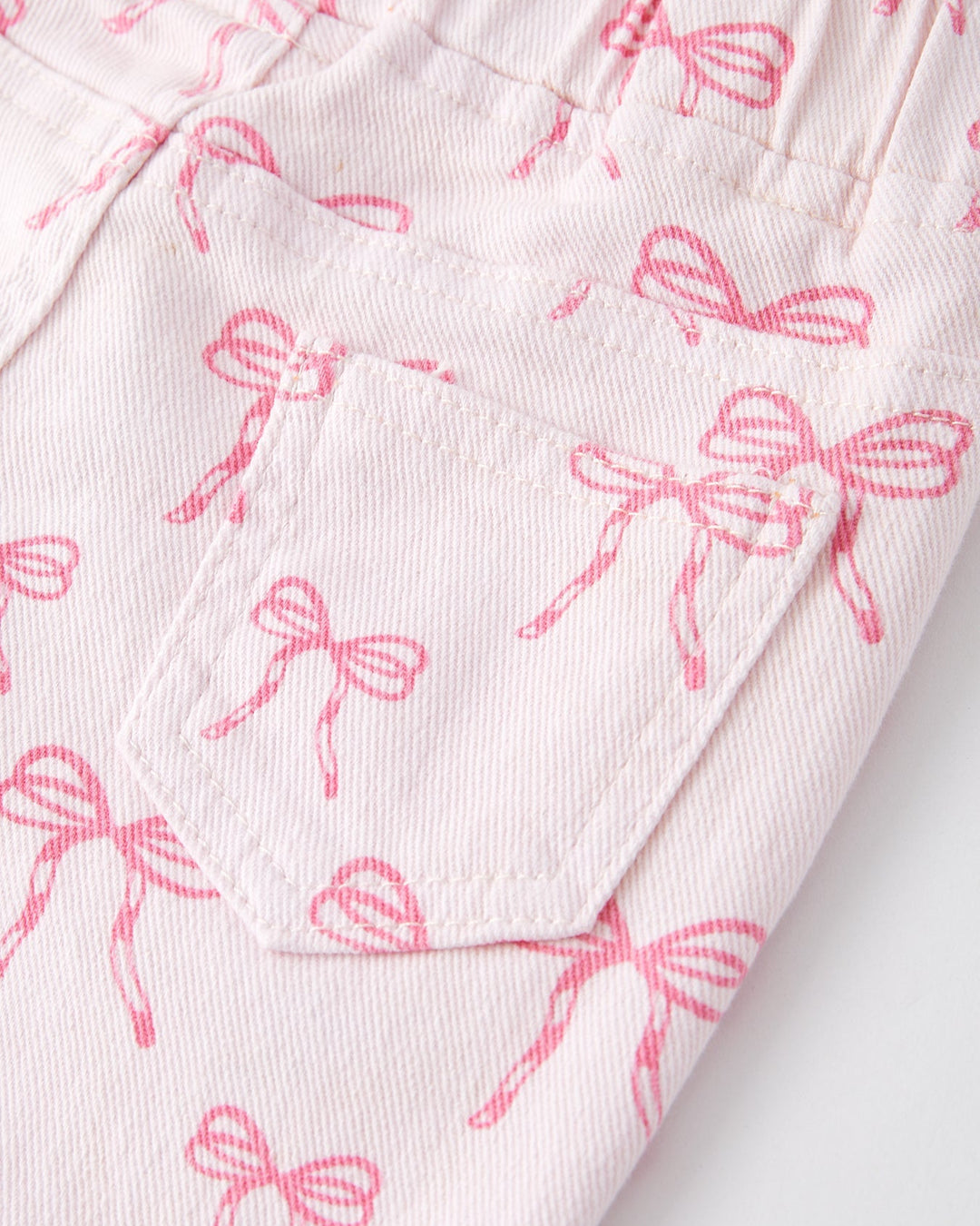 Girls flared jeans close-up: pink bow print fabric with stitched seams