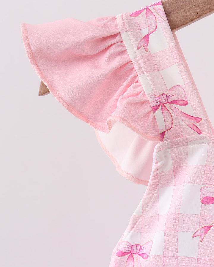 Close-up of a pink fabric with bow pattern on a light gray background