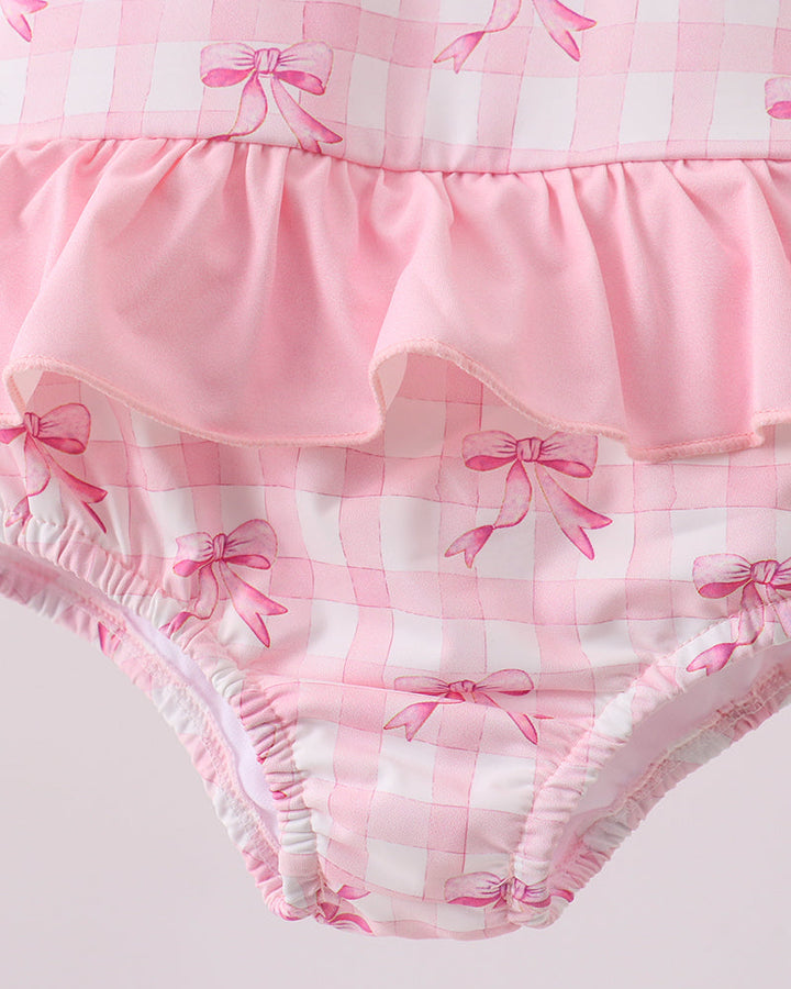 Pink checkered baby bloomers with bow pattern on a light gray background