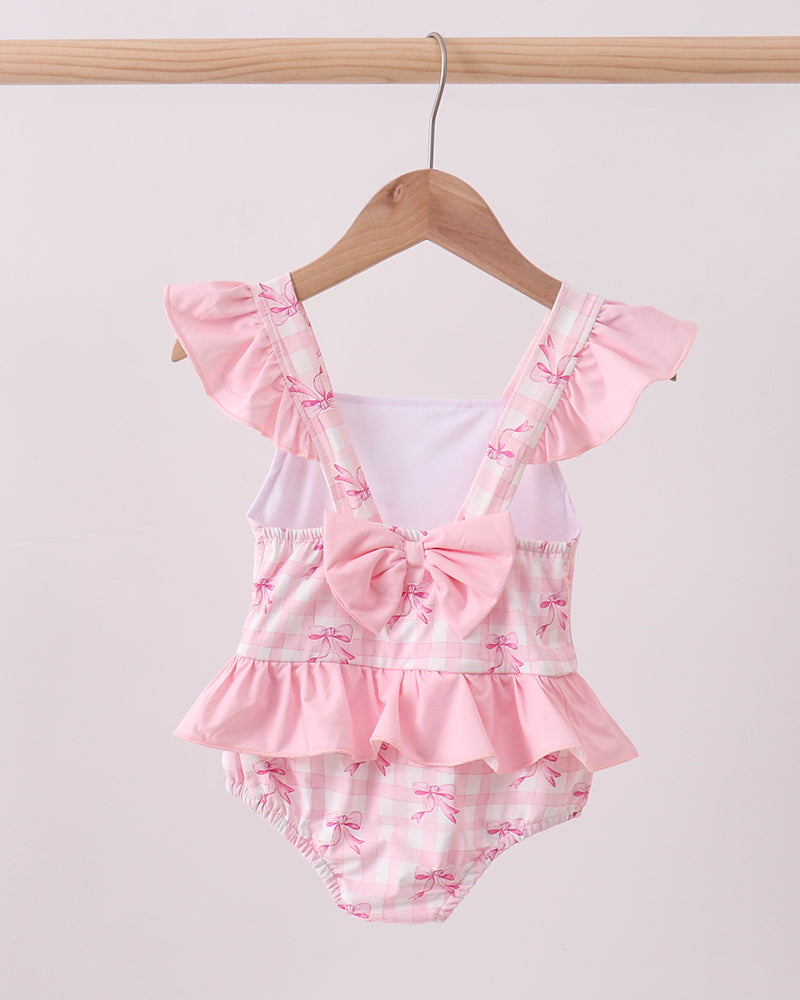 Pink Bow Print Ruffle One-Piece Swimsuit for baby girls. Hanging on wooden hanger