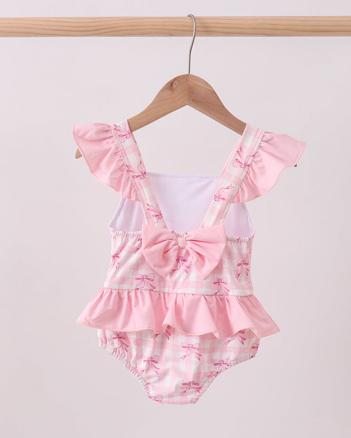 Pink Bow Print Ruffle One-Piece Swimsuit for baby girls. Hanging on wooden hanger