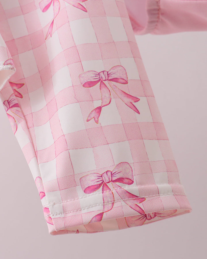 Pink checkered fabric with bow patterns on a light pink background