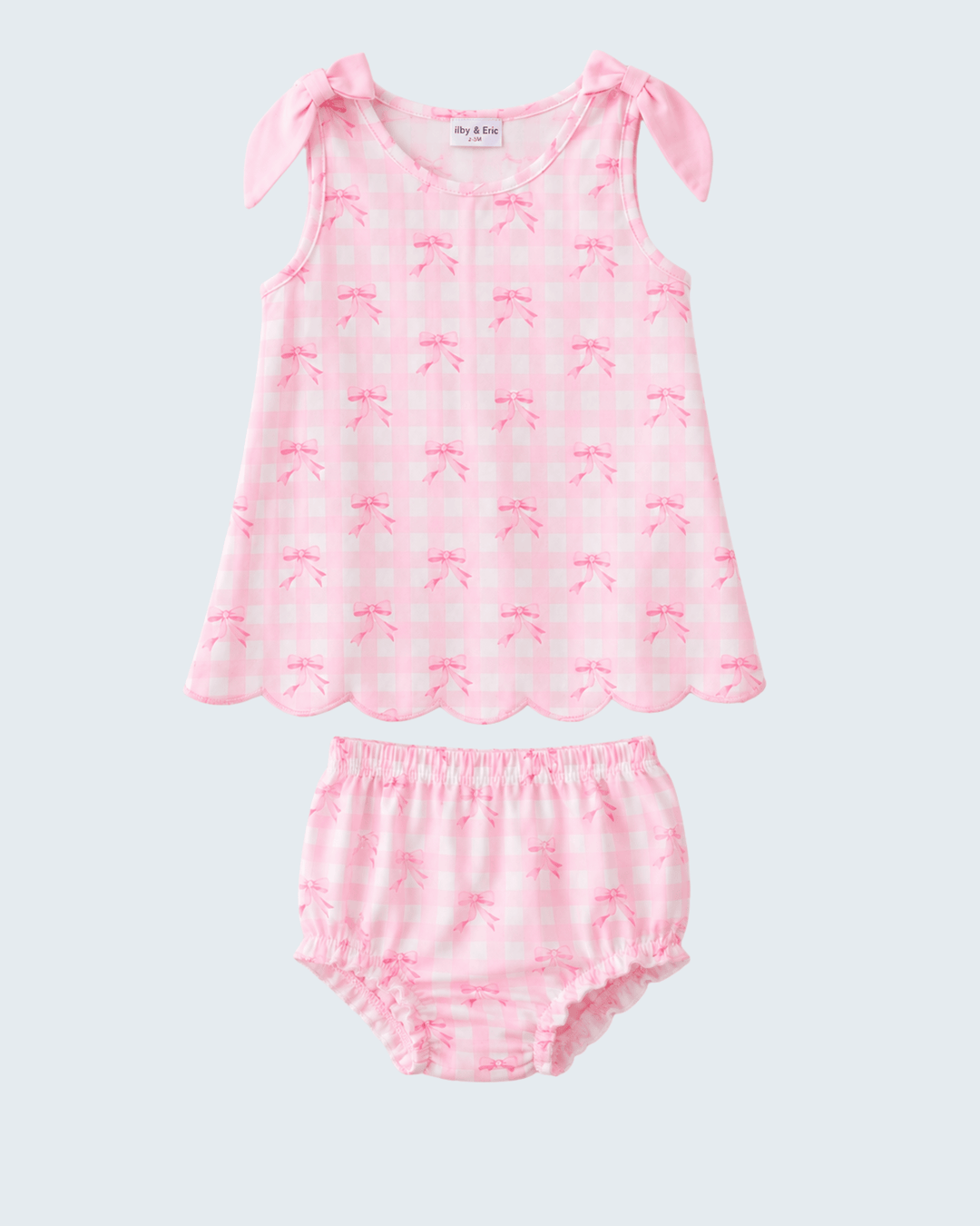 Pink baby outfit with bow design on a light gray background