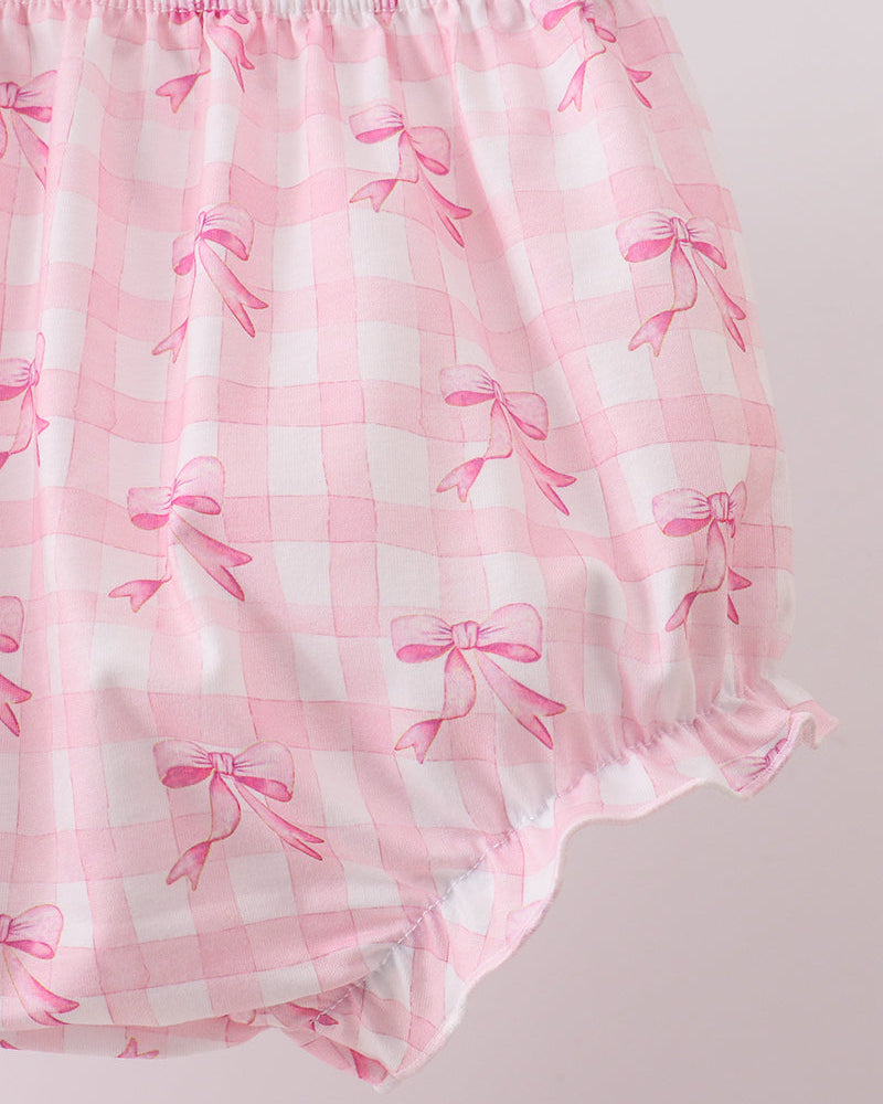 Pink baby bloomers with bow pattern on a light pink background