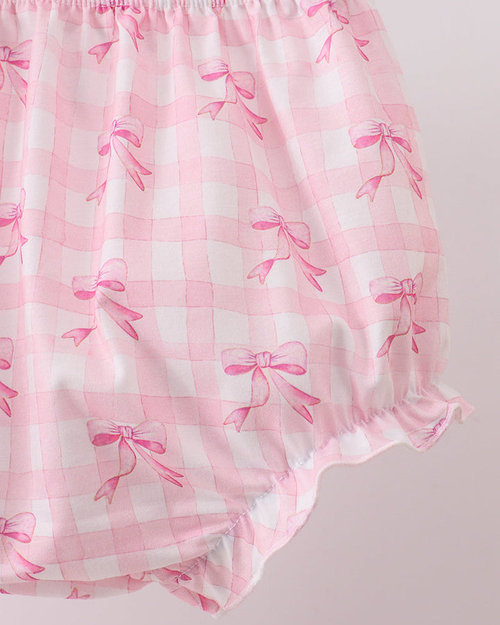 Pink baby bloomers with bow pattern on a light pink background