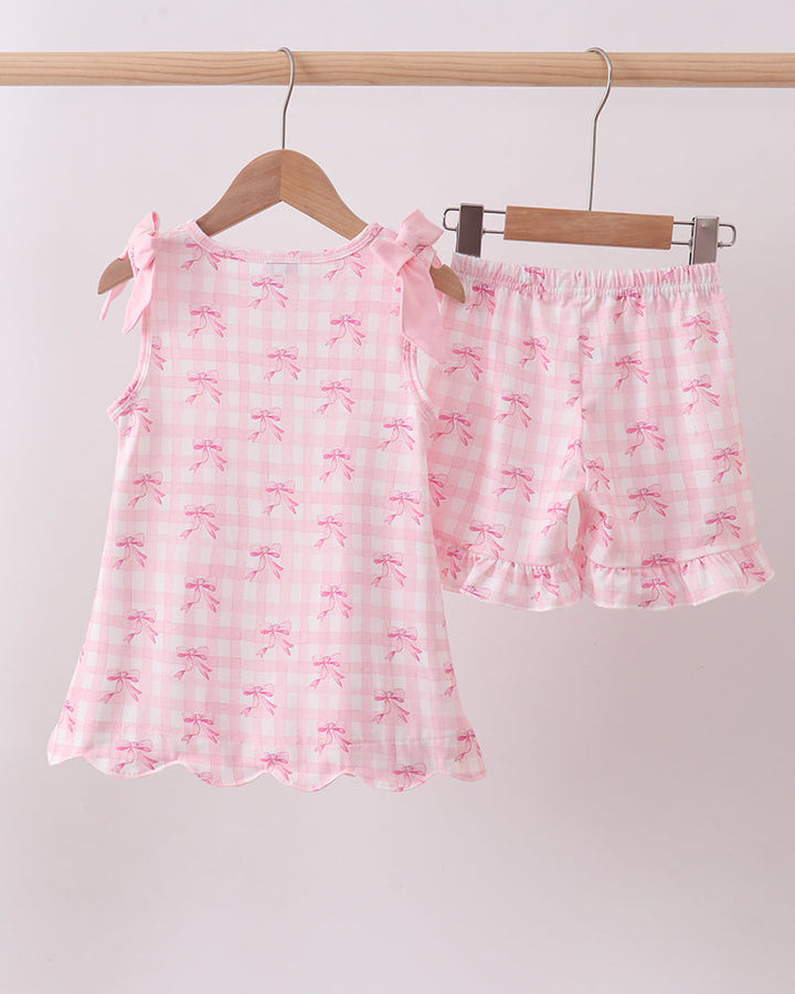 Pink shorts set with bow pattern on hangers against a white background