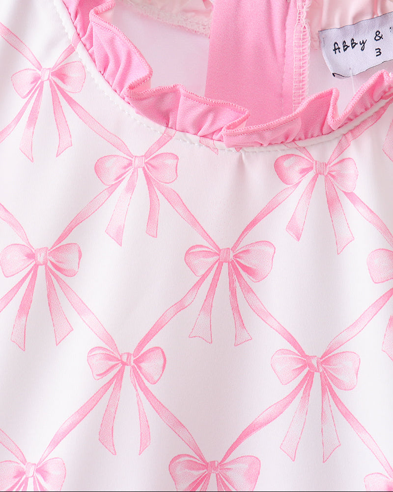 White garment with pink bow pattern and a visible label on a white background