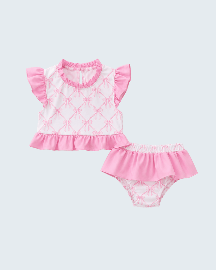 Pink baby swimsuit set with ruffled details on a white background