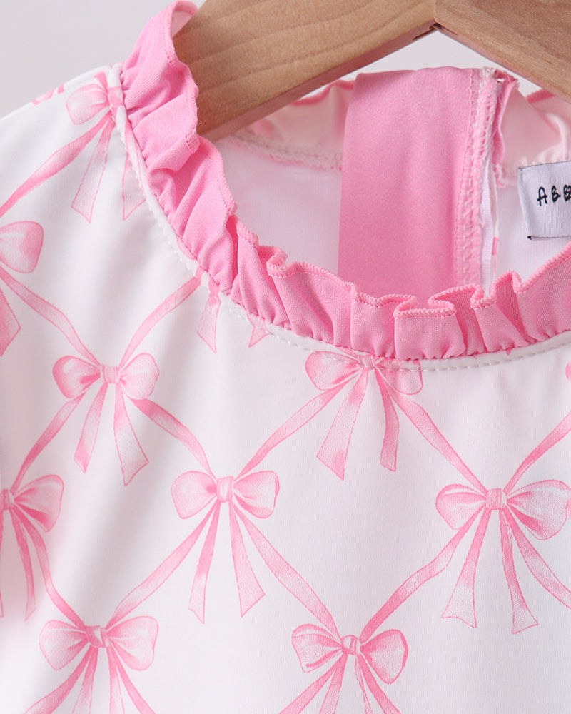 Pink and white swimsuit with bow pattern on a hanger