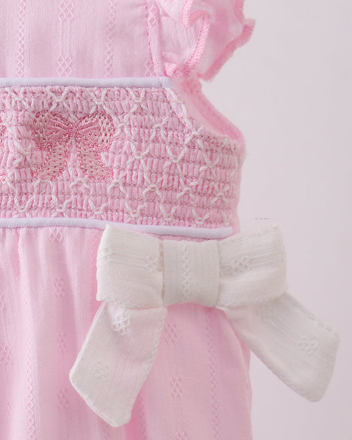 Pink textured romper with a white bow on a light pink background
