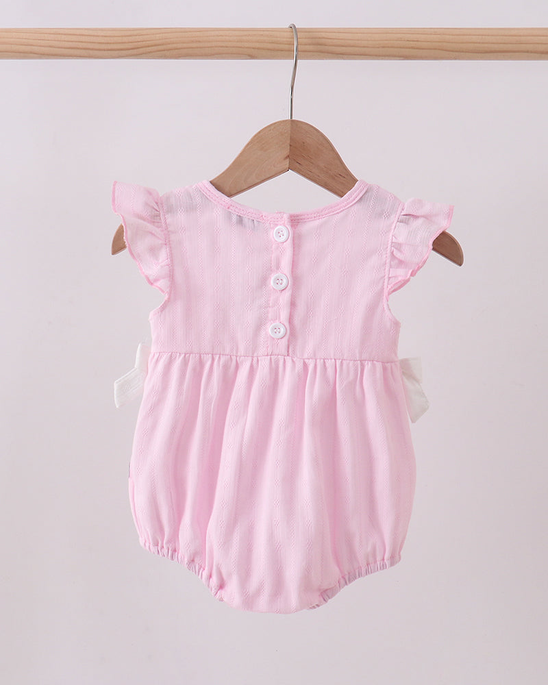 Pink baby romper with ruffled sleeves hanging on a wooden hanger against a light pink background