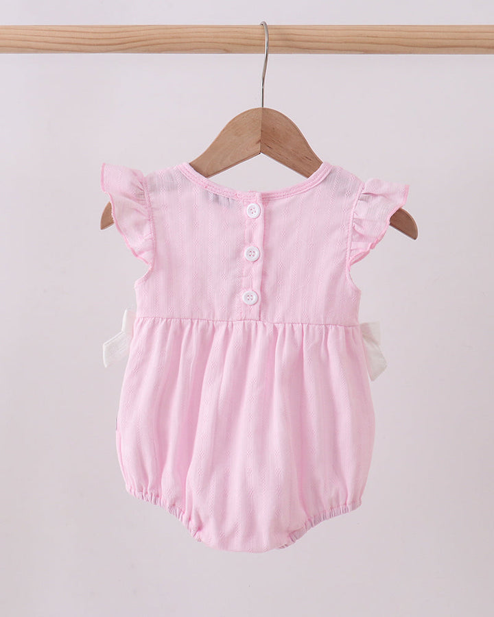 Pink baby romper with ruffled sleeves hanging on a wooden hanger against a light pink background