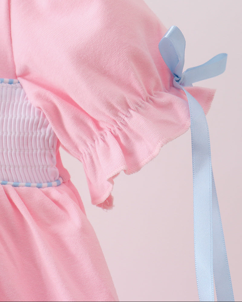 Close-up of a pink dress with a blue ribbon on a light pink background