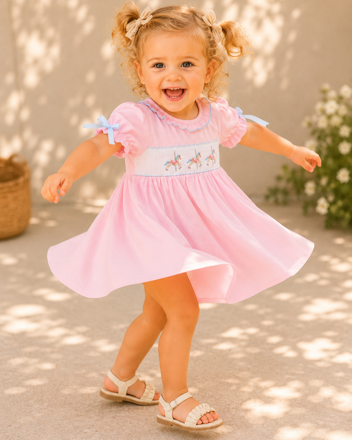 Toddler girl spinning around in sunny outdoor setting.