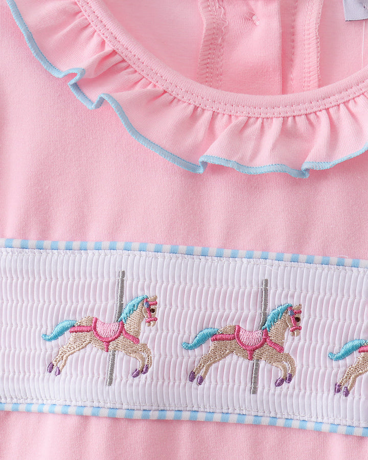 Pink dress with carousel horse design and ruffled trim on a white background