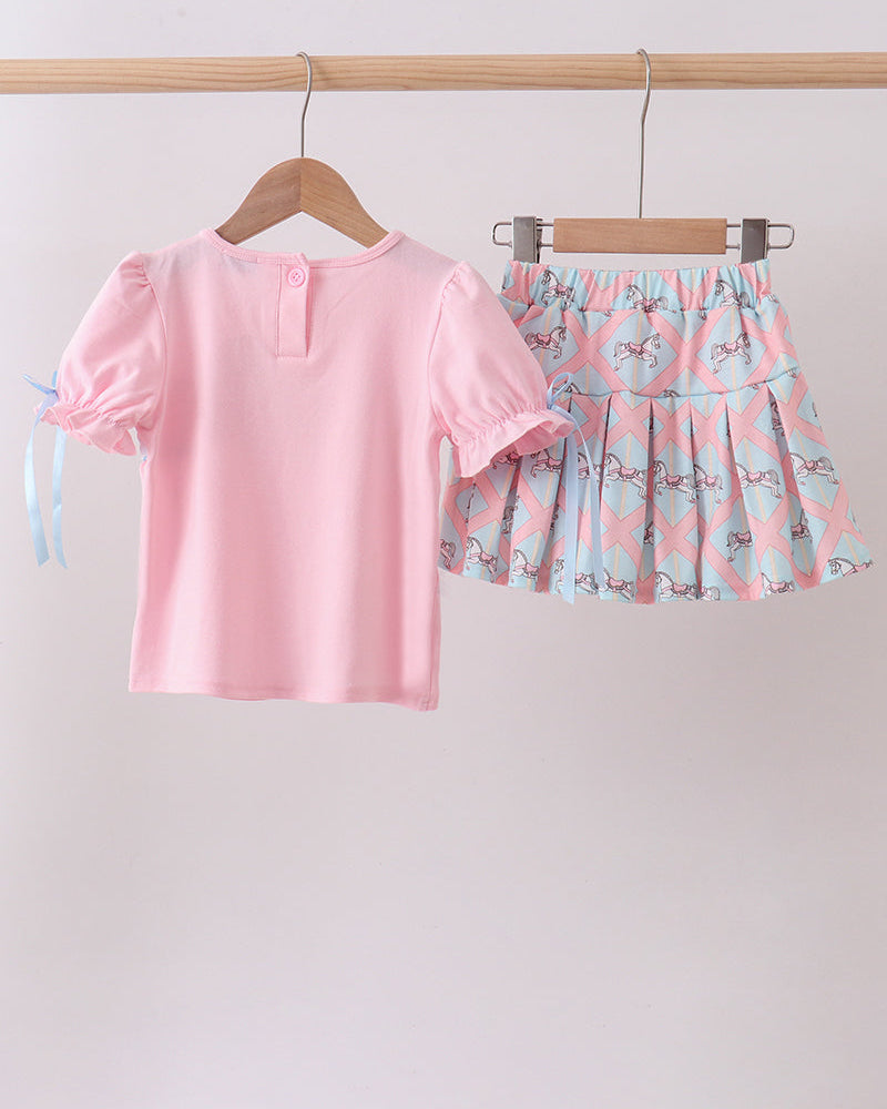 Pink top and floral skirt set hanging on a rack against a white background