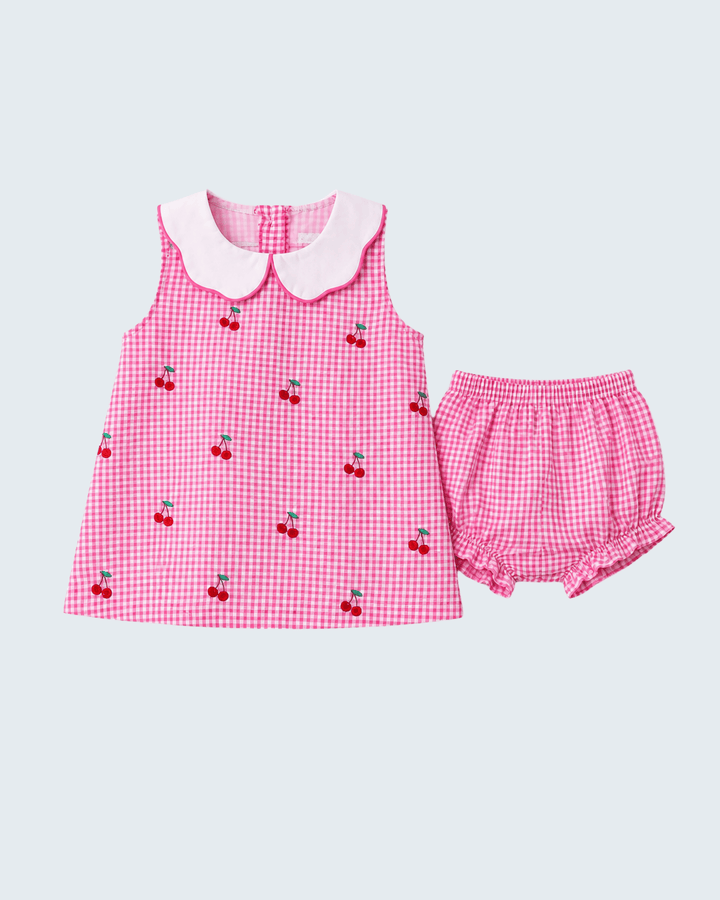 Pink checkered dress with cherry details and matching shorts on a light gray background
