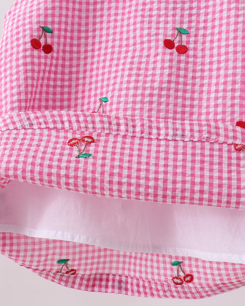 Pink gingham fabric with embroidered cherries on a white background