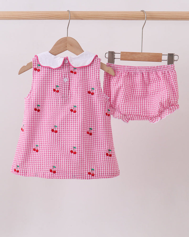 Pink checkered outfit with cherry pattern on a white background