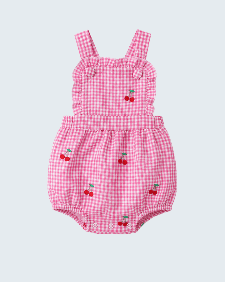Pink gingham baby romper with cherry designs on a light gray background