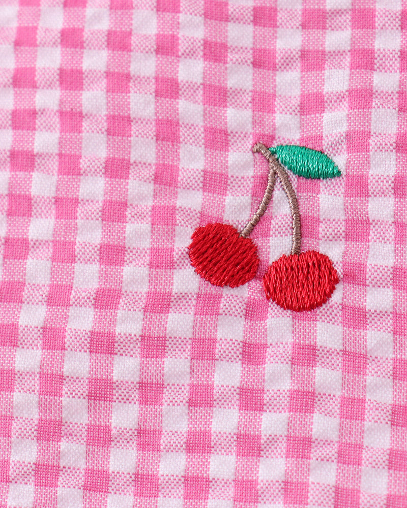 Pink and white checkered fabric with embroidered red cherries and a green leaf.