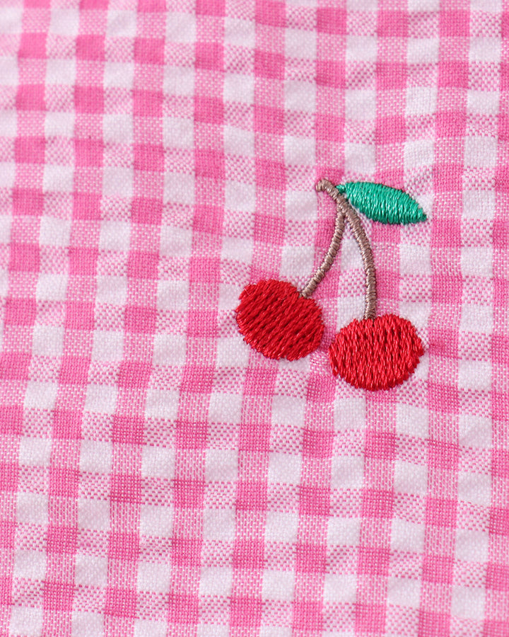 Pink and white checkered fabric with embroidered red cherries and a green leaf.