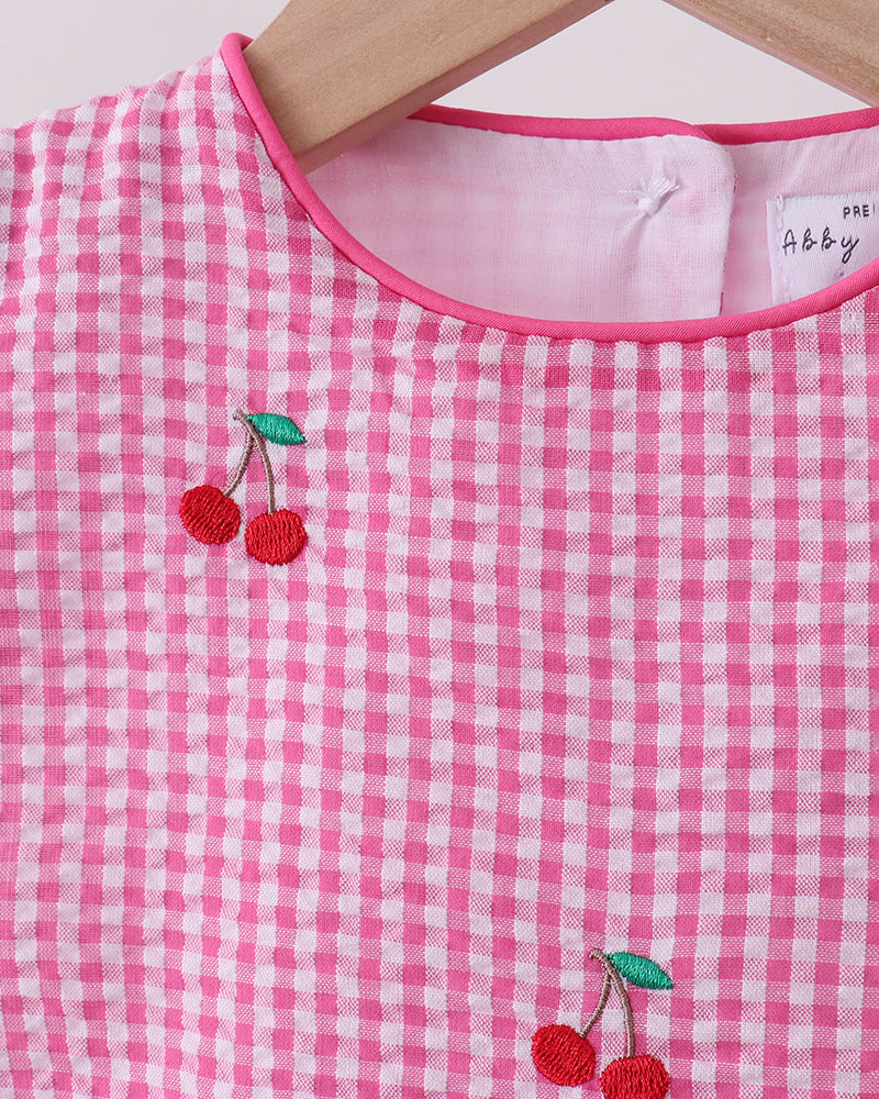 Pink gingham dress with embroidered cherries on a hanger