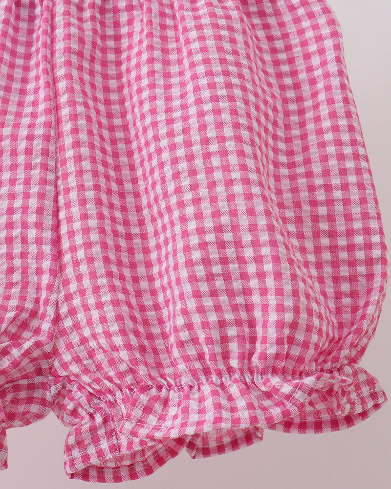 Pink and white checkered shorts with ruffled bottom on a light pink background