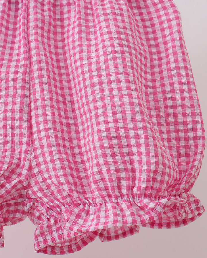 Pink and white checkered shorts with ruffled bottom on a light pink background
