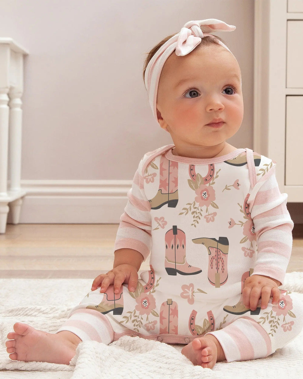 Pink patterned long-sleeve romper on baby, crew neck with footed legs
