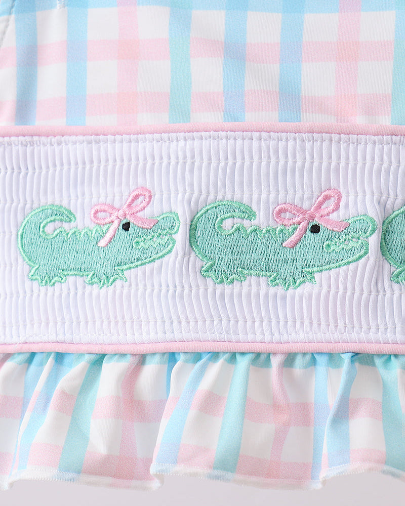 Smocked gingham swim bottoms with green crocodile embroidery and pink ruffle waistband