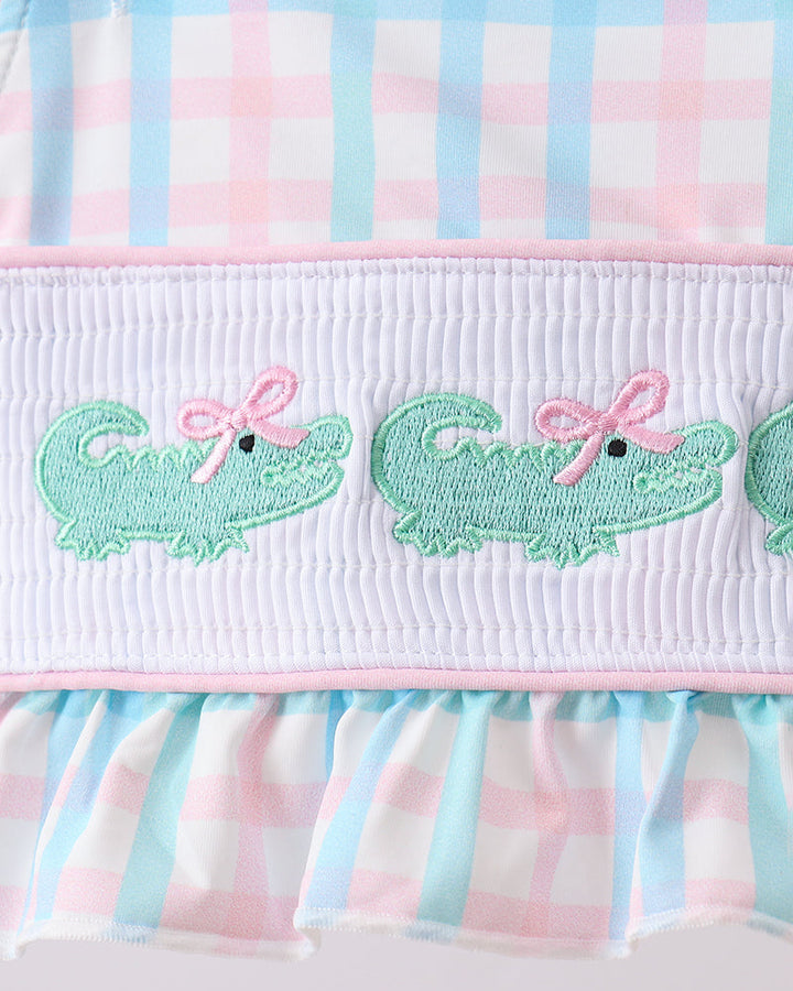 Smocked gingham swim bottoms with green crocodile embroidery and pink ruffle waistband