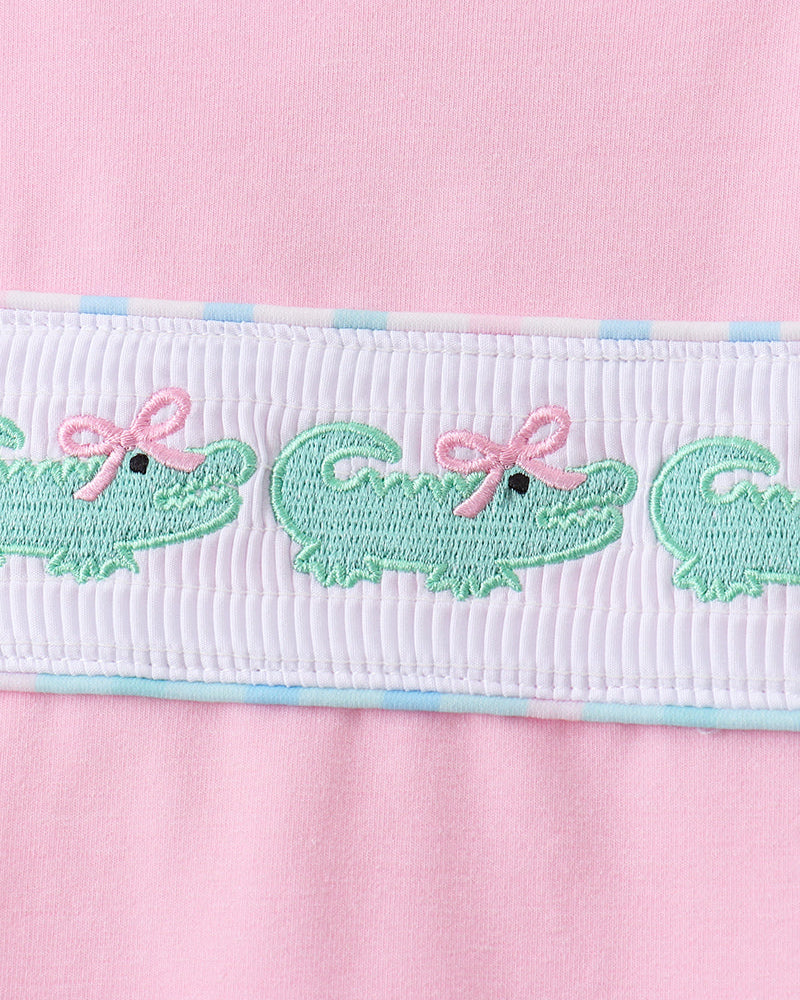 White smocked waistband with green embroidered crocodiles on pink skort