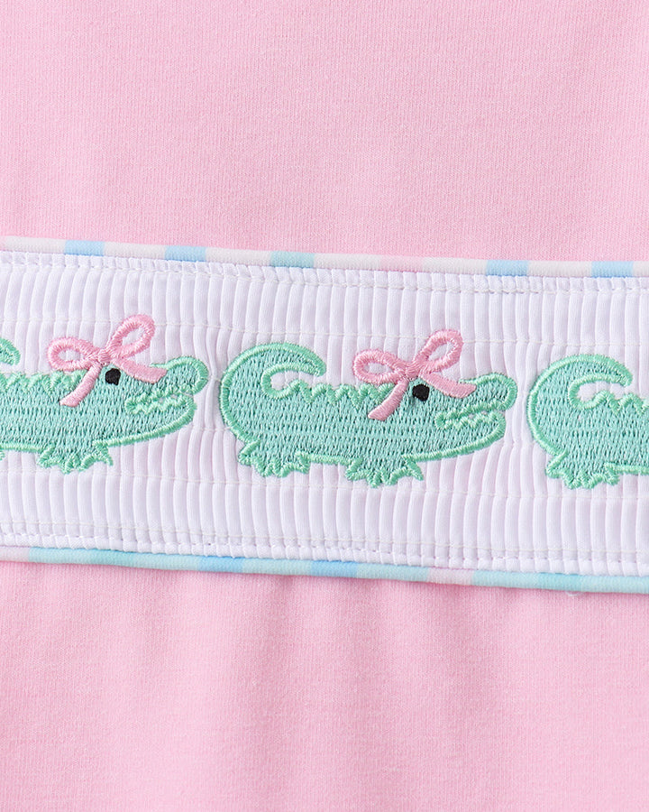 White smocked waistband with green embroidered crocodiles on pink skort