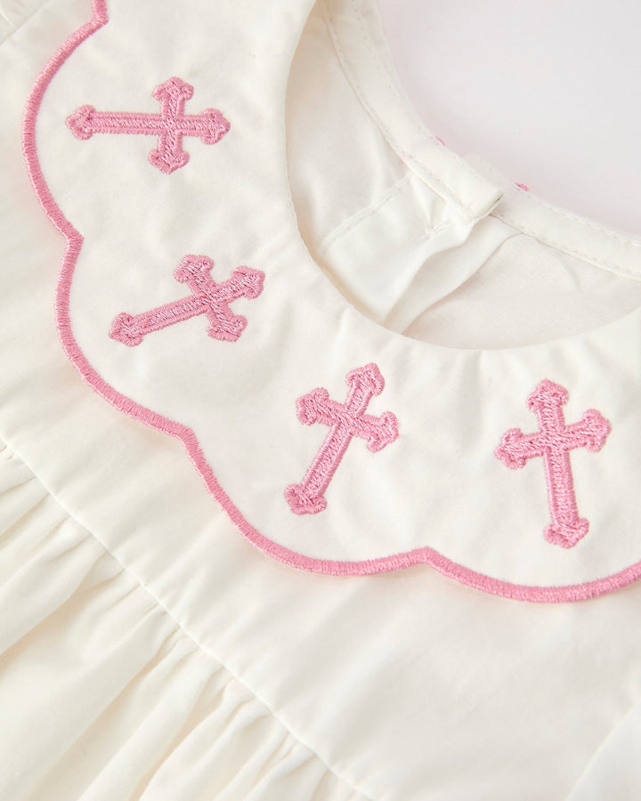 White christening dress bib with pink cross embroidery and scalloped pink edge