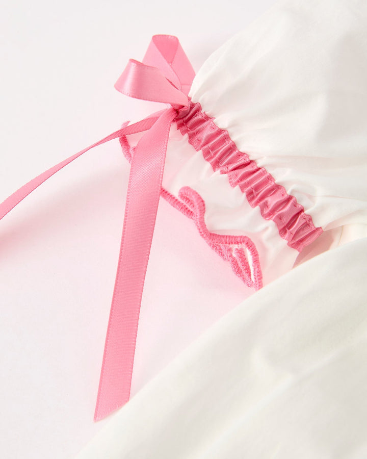 White dress sleeve with pink ribbon bow and gathered ruffle trim