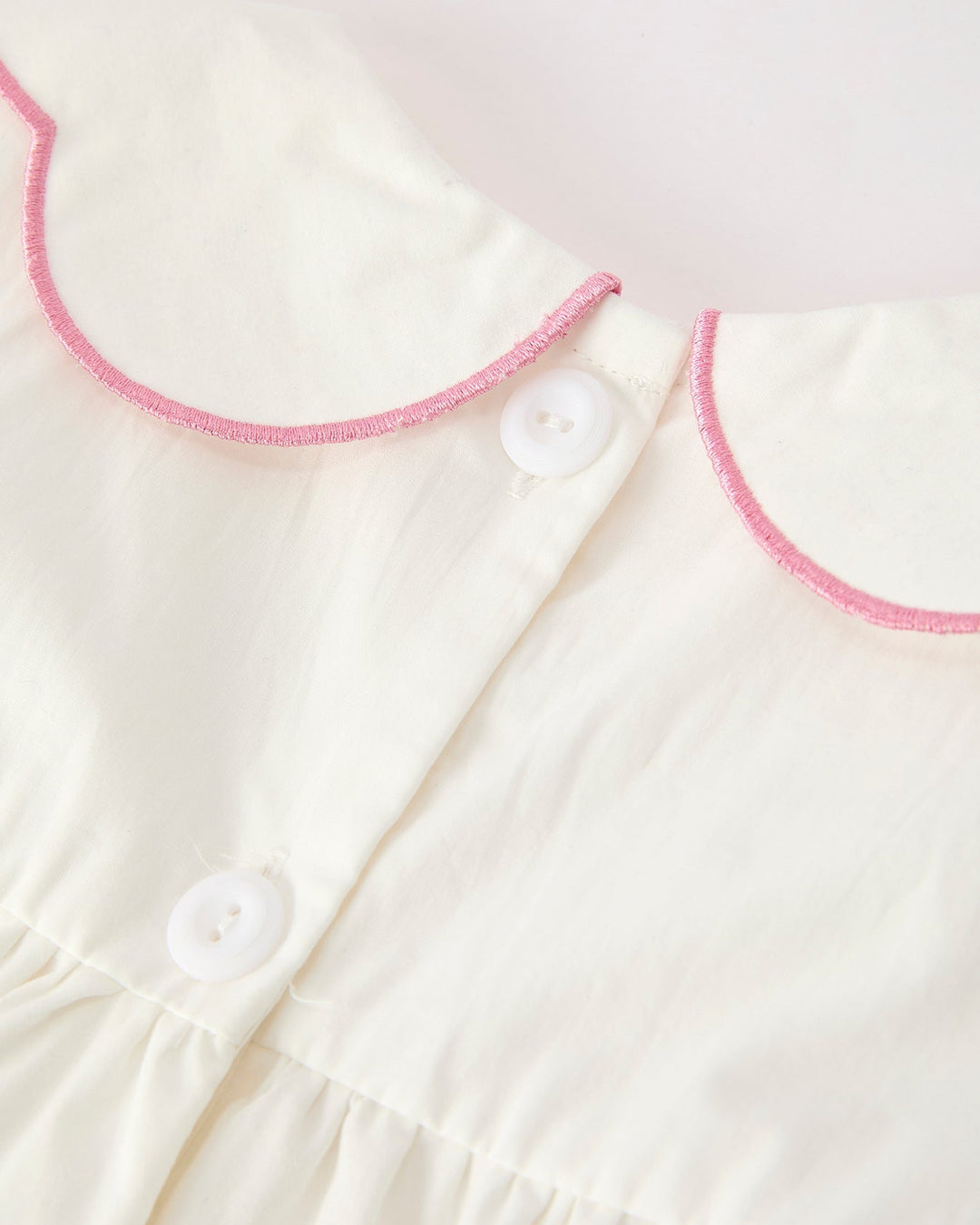 Girls cream christening dress with pink-trim button placket and Peter Pan collar
